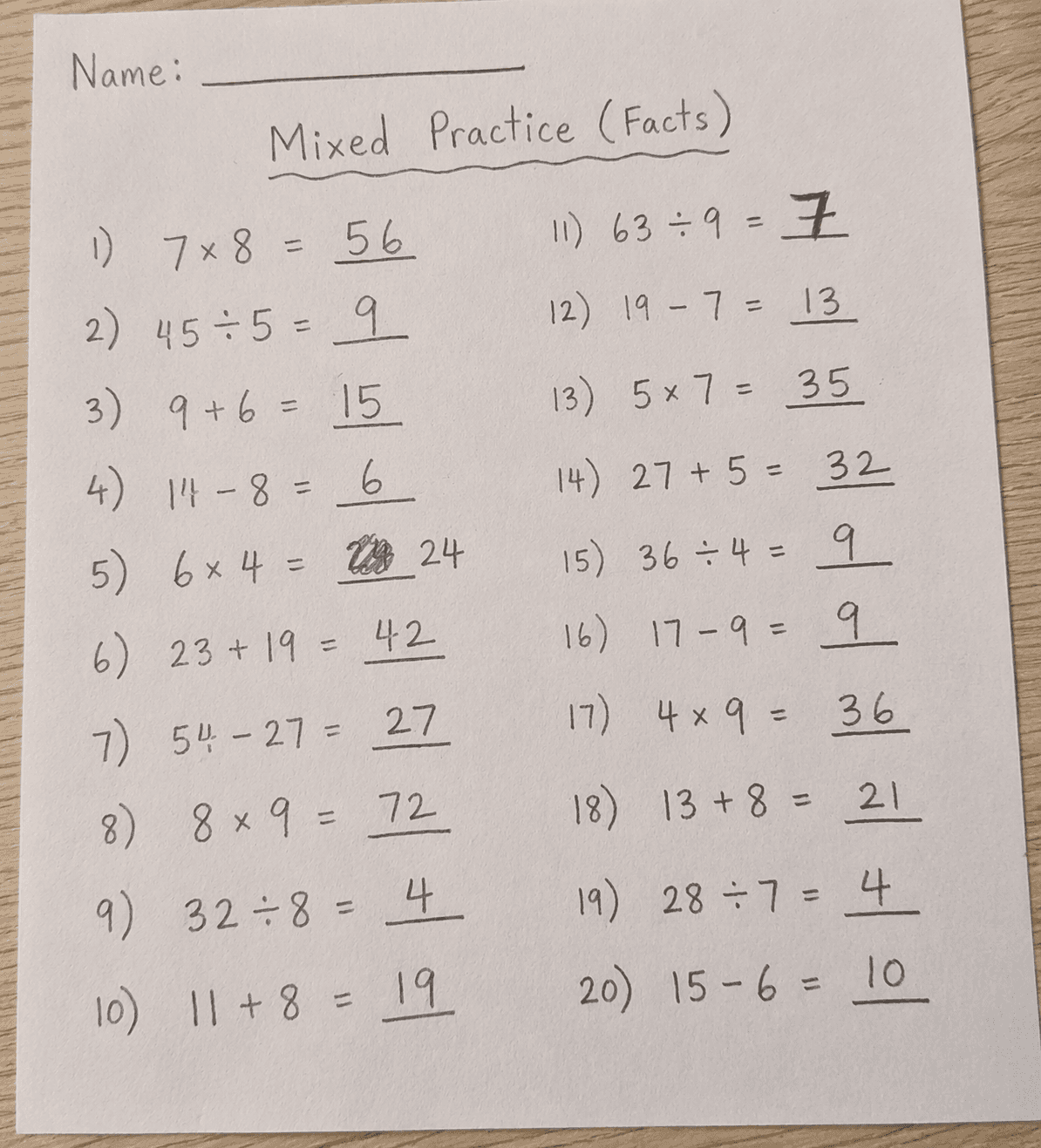 A handwritten mixed math practice worksheet showing addition, subtraction, multiplication and division problems